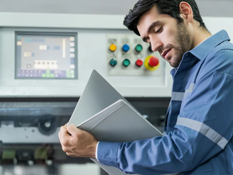 Técnico avaliando equipamento industrial com falha em chão de fábrica